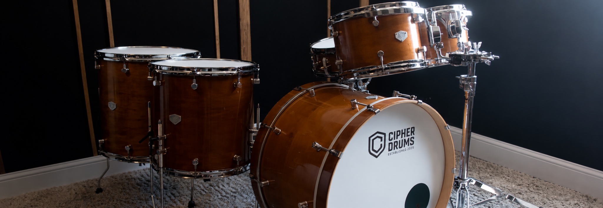 A full Cipher Drums kit in the workshop — honey maple, Cipher-branded bass drum head